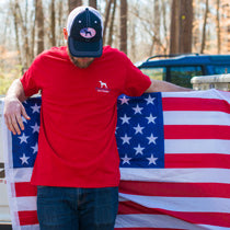 A man wearing a Straight Up Southern t-shirt holds an American flag