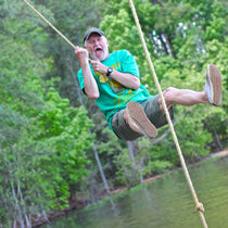 A man shouts with excitement while swinging on a rope over water