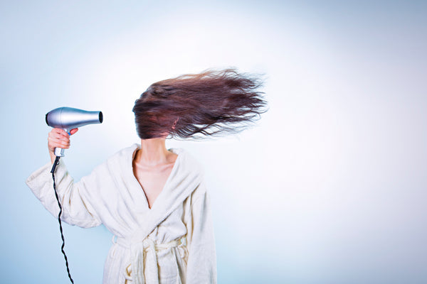 Lady drying long dark brown hair with hair dryer