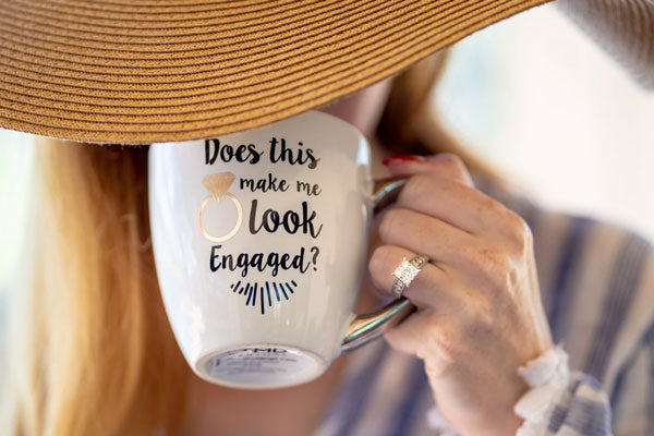 Woman with large engagement ring sips from a coffee mug