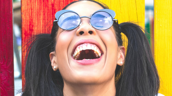 young woman open-mouth laughing in front of a colourful background