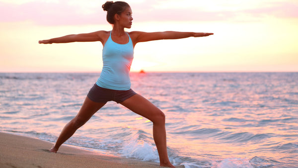 woman on the beach doing warrior pose yoga