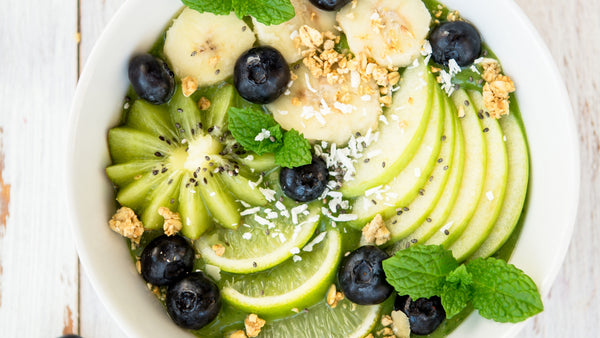green smoothie bowl toped with kiwi blueberries apple and mint