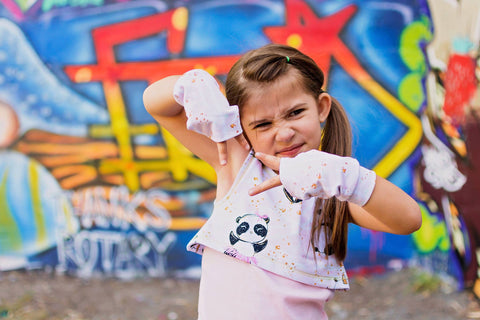 badass girl in front of graffiti wall with fingerless gloves on and a panda shirt