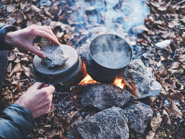 A titanium pot over a small fire in the woods