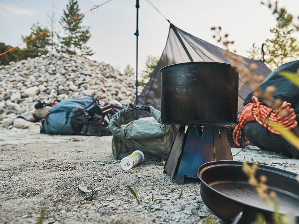 A titanium pot sitting on top of a lightweight stove in front of an assortment of ultralight backpacking equipment