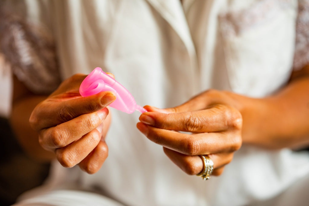 Woman folding BeYou menstrual cup in hand 