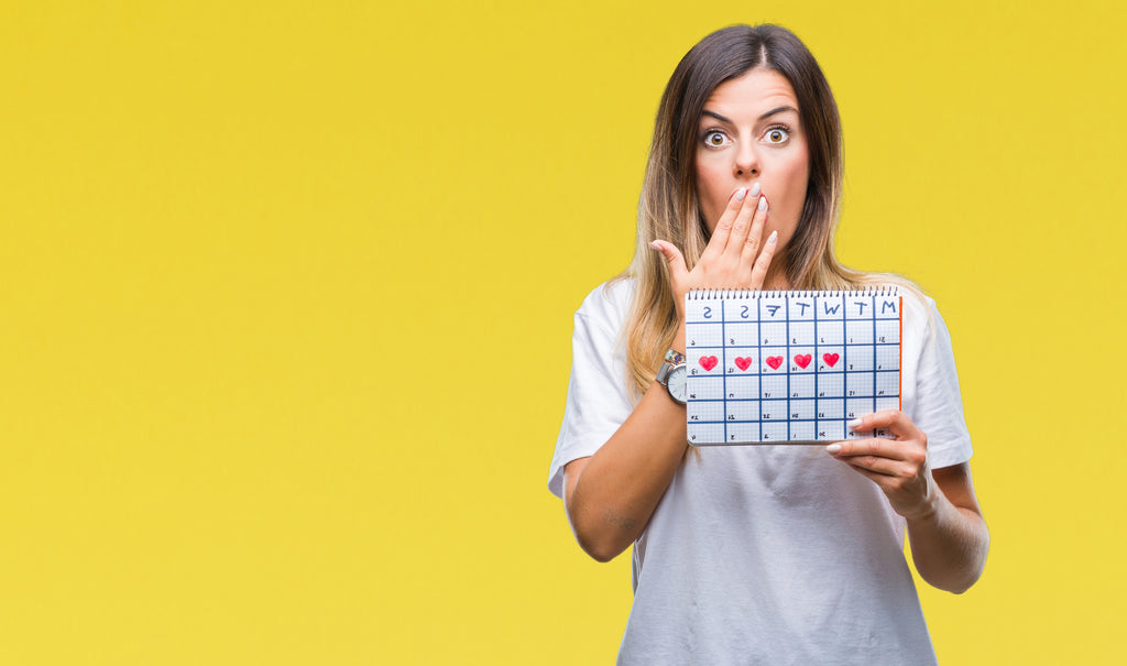 Woman holding up calendar with her period days on it 