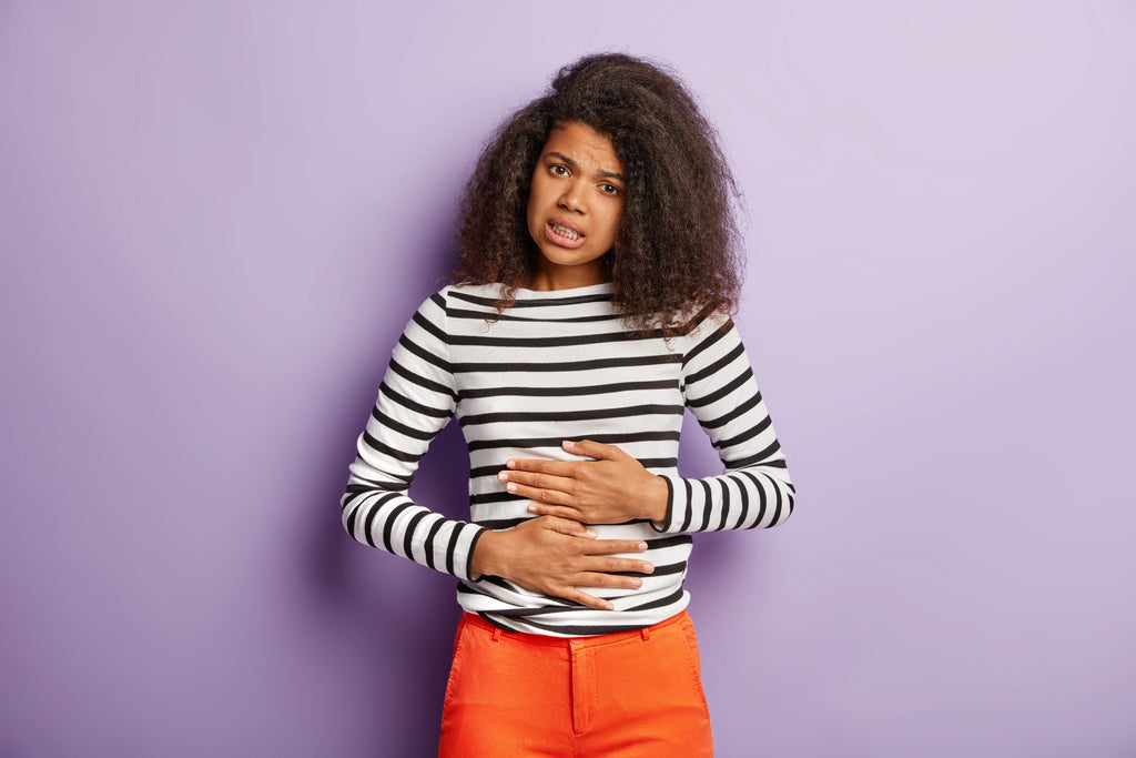 Young black woman holding stomach in pain 