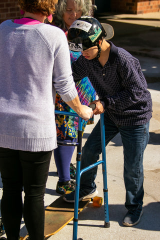 Using Walker to Help Student Stand on Longboard