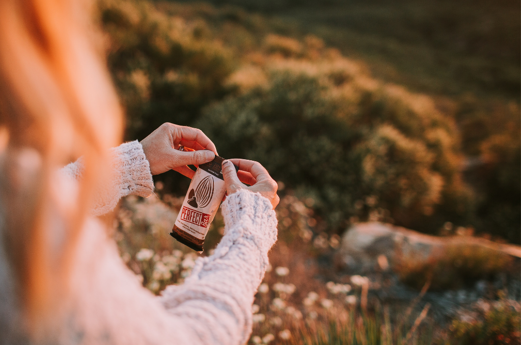 Woman sitting outside eating a nutrition bar type snack