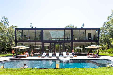 Glass house with tall windows overlooking a pool party