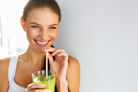 Happy brunette woman drinking organic green smoothie 