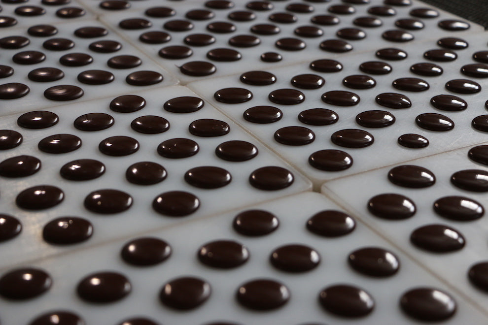 Photograph of mass-produced chocolates that are all of the same size and consistency.