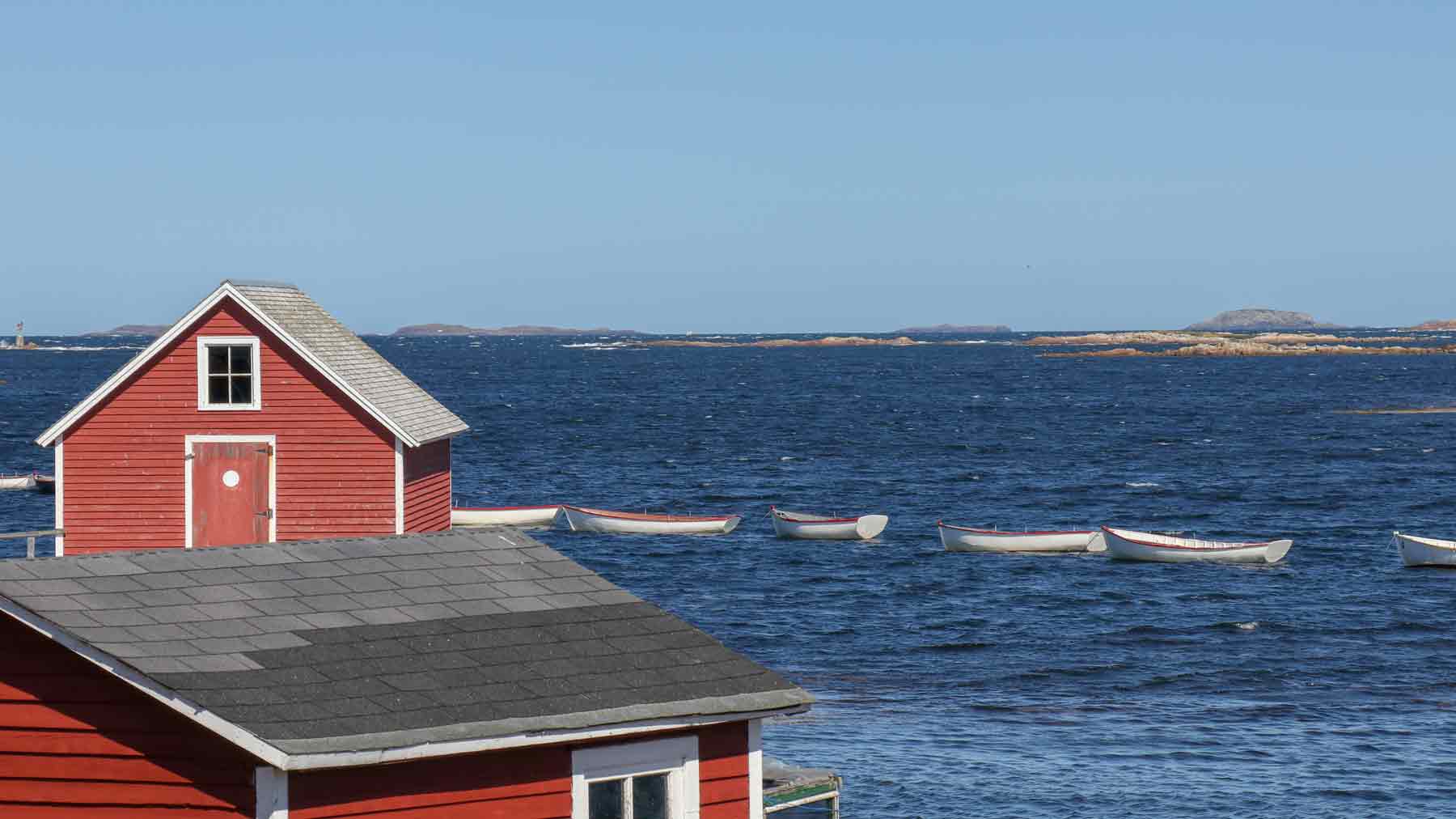 Red wooden fishermen's sheds in front of the ocean on Fogo Island