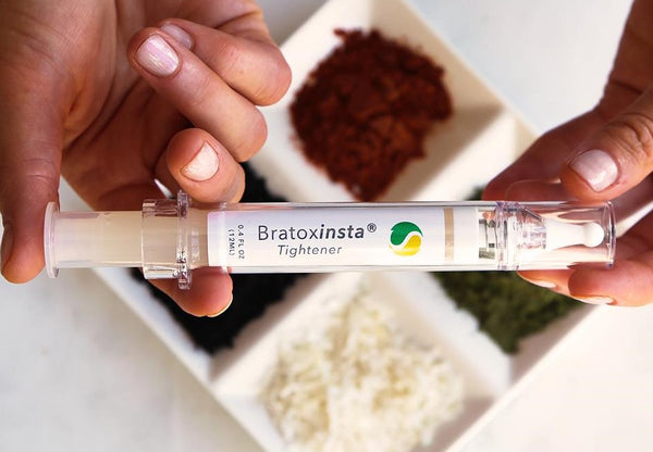 Hands holding Bratoxinsta eye serum over natural ingredients.