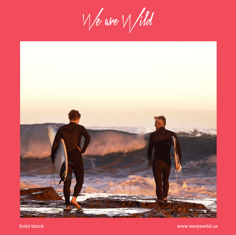 Alt text: Two people with surfboards walk towards the waves.