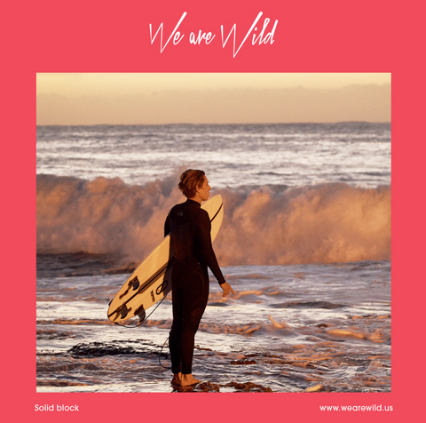 alt text: A person holding a surfboard looks at the water as the sun sets.