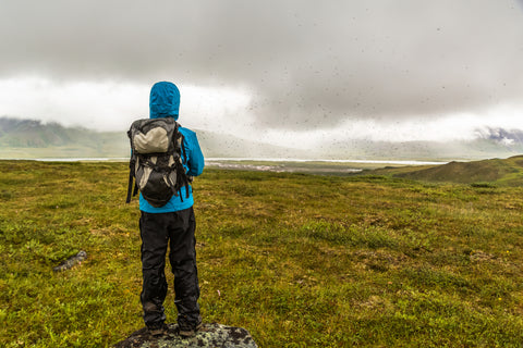 A hiker stares off into the distance during a rainstorm in Alaska.