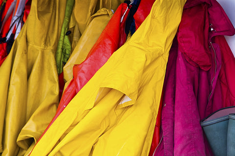A row of rain jackets hang on a shelf.