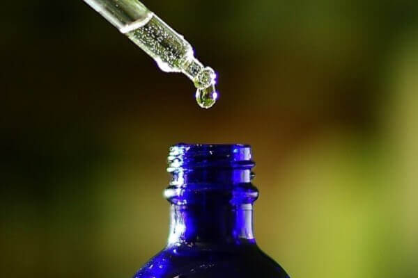 Serum in dark blue glass bottle with glass dropper
