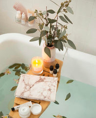 Bathtub with a tray with candles, diary, plant