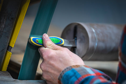 A New West KnifeWorks knife passes through a grinding machine