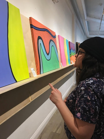 Salina Mendoza (SAM) abstract geometric artist looking at her art pieces at 1888 Center