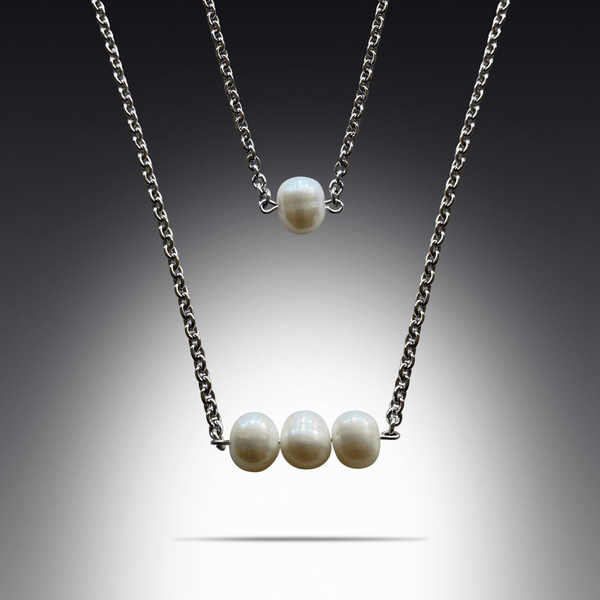 This is a photo of two freshwater pearl necklaces layered. they are single pearl necklace and three pearl pendant necklace.