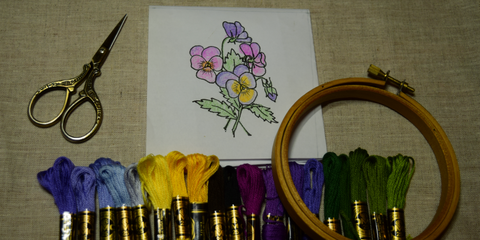 Pansy embroidery design with DMC embroidery floss, hoop, and scissors