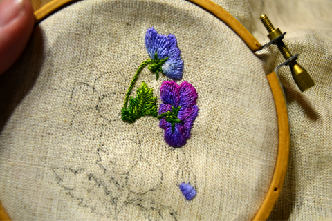 Embroidered pansies worked in purple on oatmeal linen in a hoop