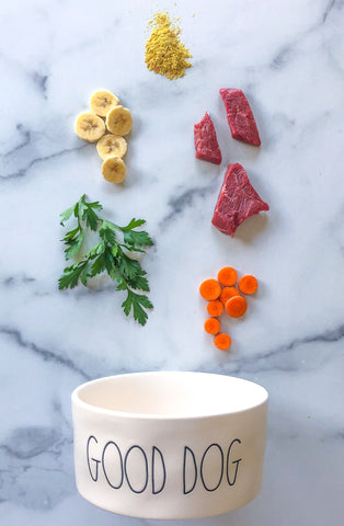 raw dog food ingredients, including carrots, bananas, and red meat