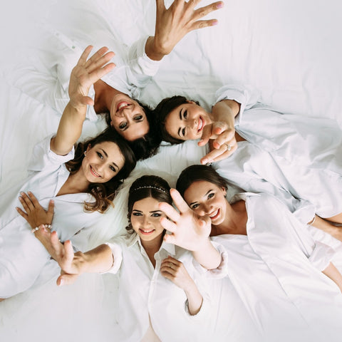 bride and bridesmaids are laying on the bed
