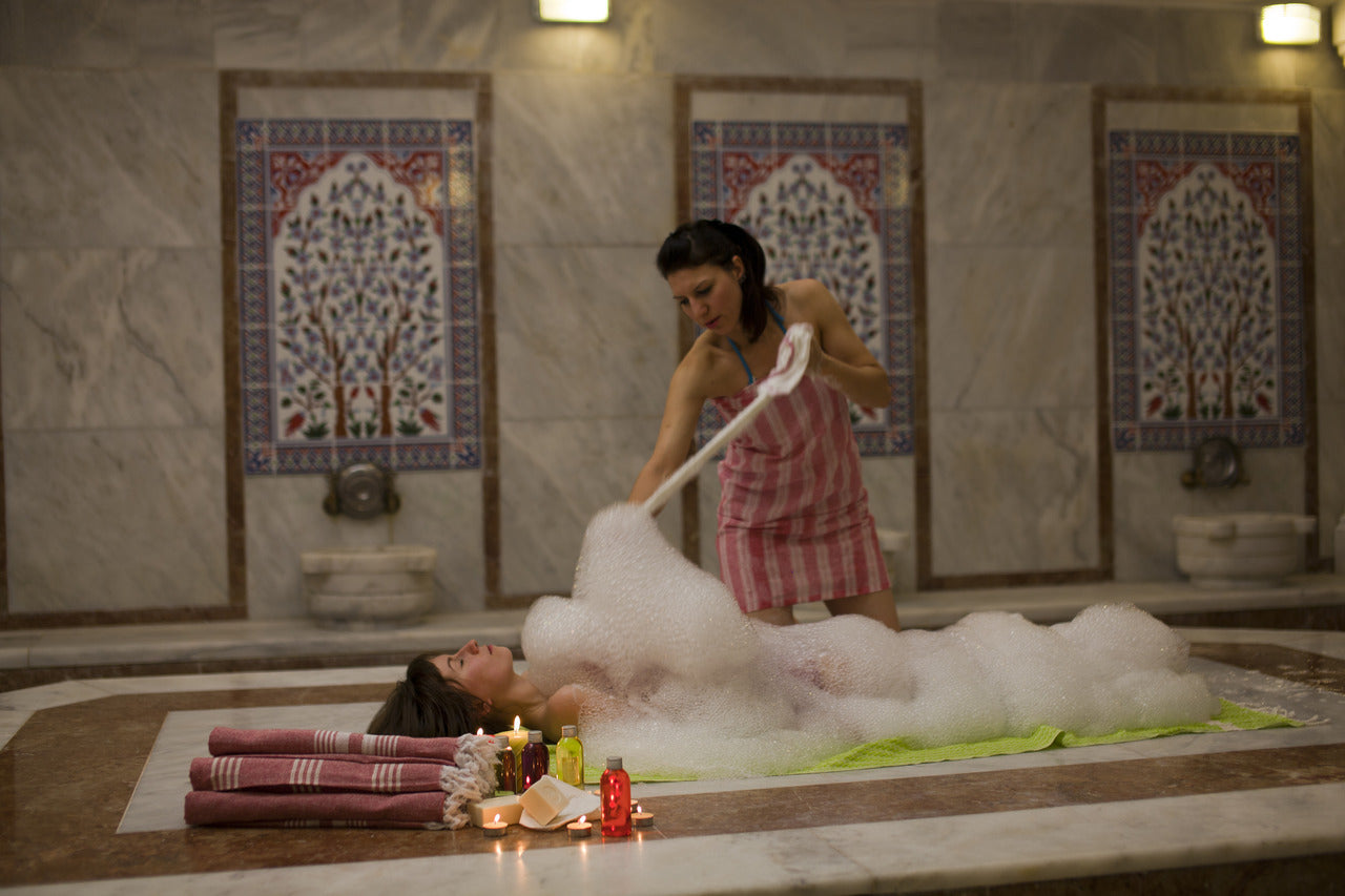 woman bathing with a foam in hammam