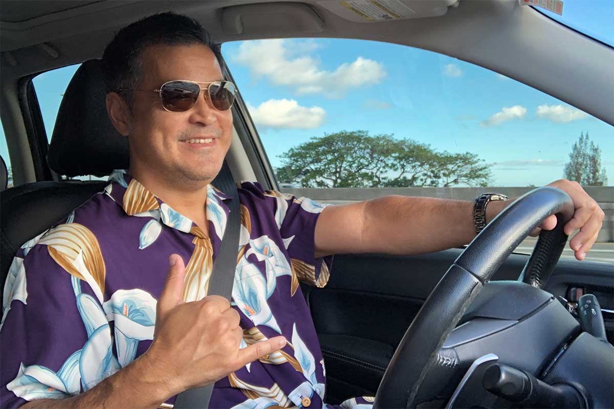 driving in a purple Calla Lily Magnum PI Hawaiian shirt