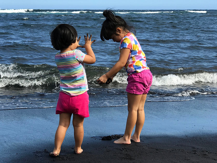 kids playing with the black sand at Punalu'u Beach