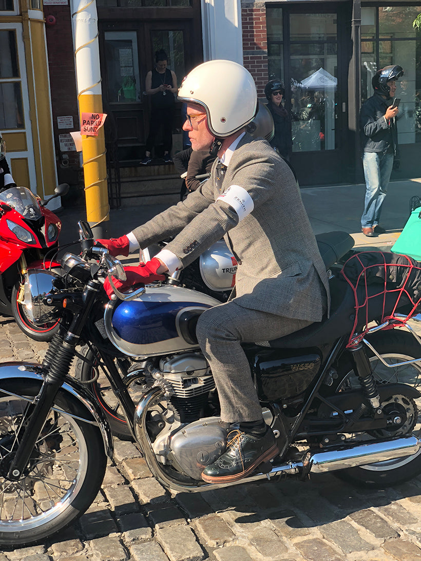 Man in suit riding vintage motorcycle on the street