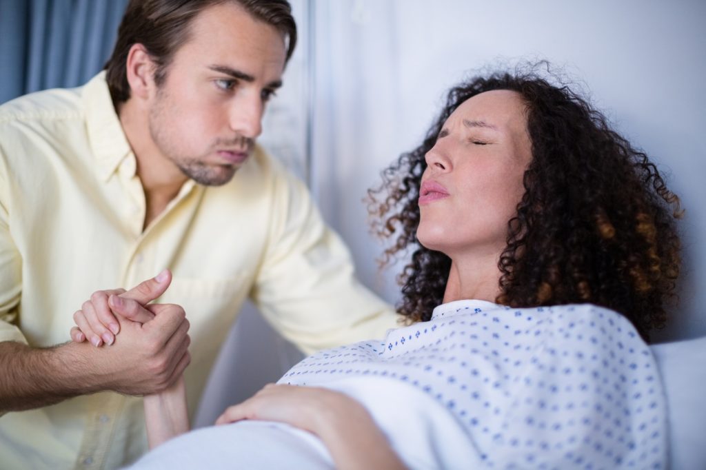 Man comforting pregnant woman during labor in ward