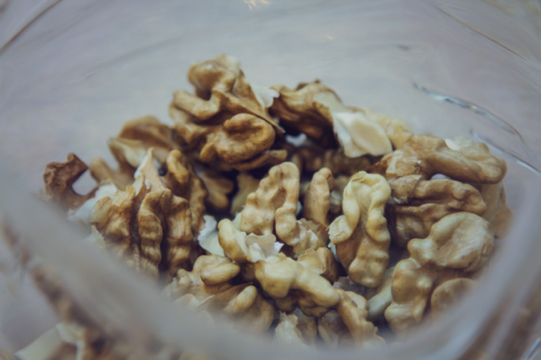 A pile of walnuts in a plastic tub ready to be placed on top of a cake.