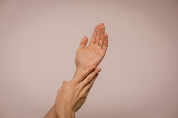A person touching their left hand with their right hand feeling their skin. 