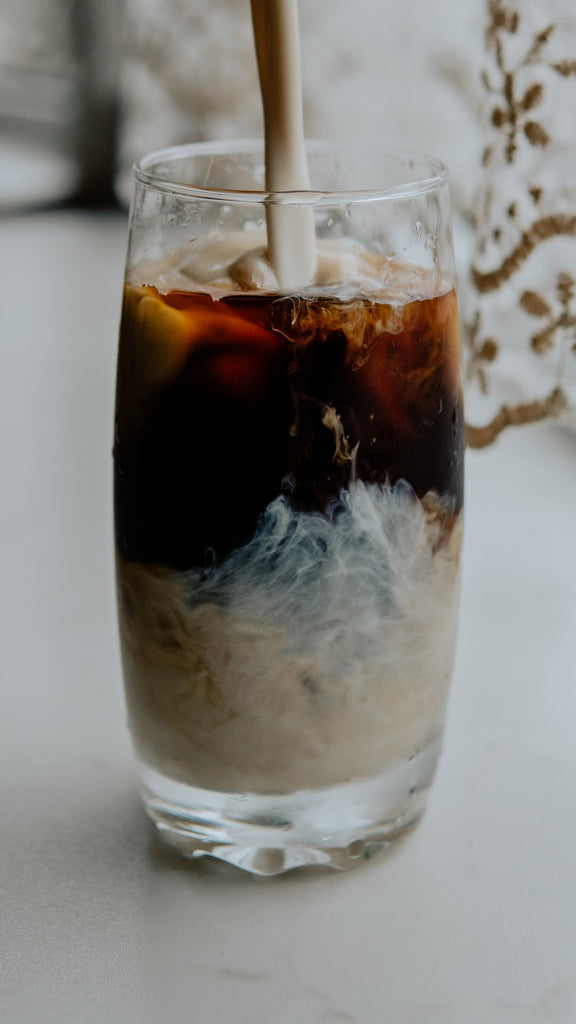 condensed milk poured into a Thai iced coffee