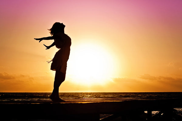 A person standing on a beach with the wind in their hair as the sun shines. 