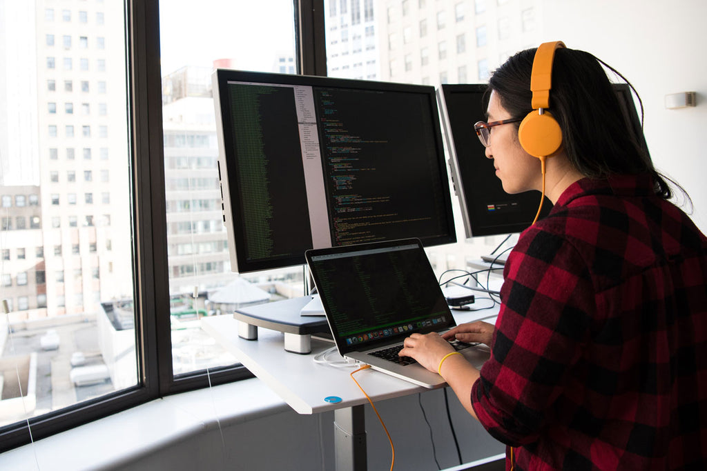 Woman coding on dual screen in office