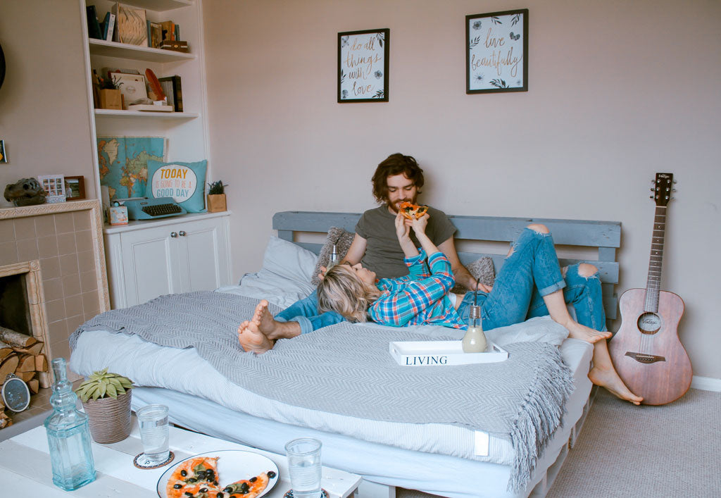 Young couple having fun on bed eating pizza