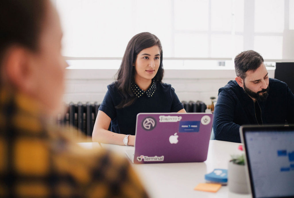 Woman sitting in conference room with colleagues and laptop