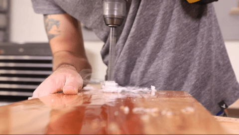 Person drill a hole into a large piece of wood