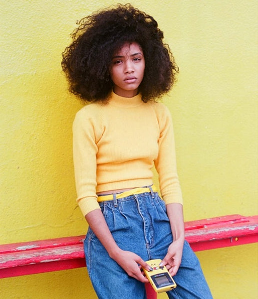 Girl in 90s streetwear fashion holding a Gameboy console.