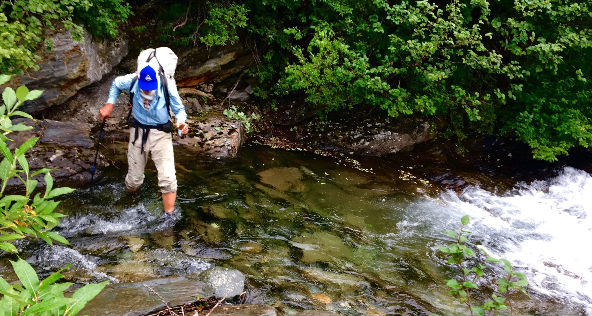 Ultralight backpacker crossing a river by foot