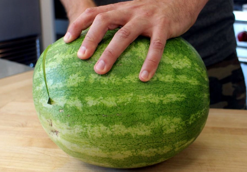 Cutting the end of the watermelon at an angle slightly off vertical