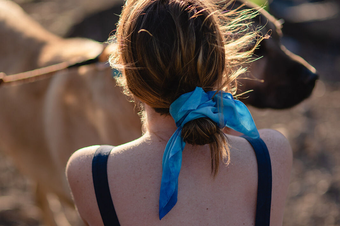 Image of white woman from the back, wearing her hair tied in a bun with silk bandana